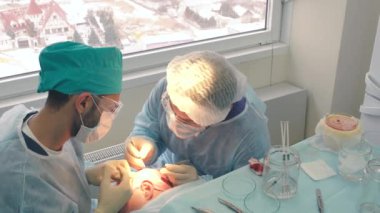 Kellik tedavisi. Saç ekimi. Ameliyathanedeki cerrahlar saç nakli ameliyatı gerçekleştirin. Saç köklerini başın bir kısmından hareket ettiren cerrahi teknik.