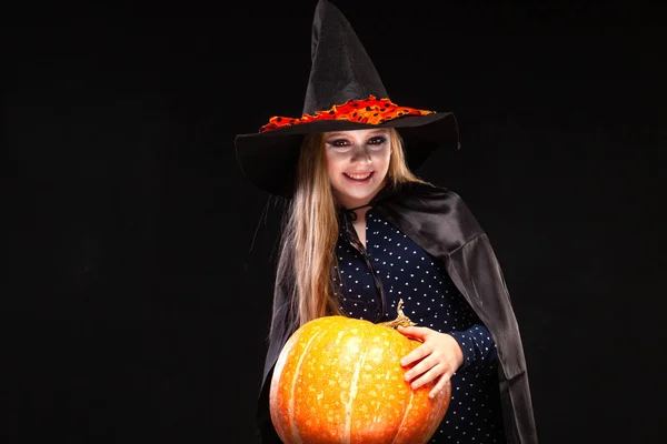 Bruja de Halloween con calabaza sobre fondo negro. Hermosa joven sorprendida mujer en sombrero de brujas y traje de calabaza celebración. Amplia fiesta de Halloween diseño de arte. Copia y pega. Concepto de bruja. Araña —  Fotos de Stock