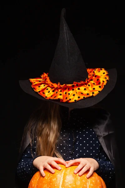 Bruja de Halloween con calabaza sobre fondo negro. Hermosa joven sorprendida mujer en sombrero de brujas y traje de calabaza celebración. Amplia fiesta de Halloween diseño de arte. Copia y pega. Concepto de bruja. Araña —  Fotos de Stock