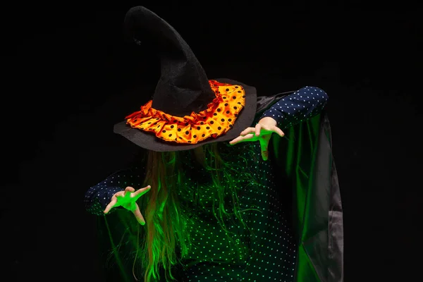 Bruxa de Halloween sobre um pote de líquido brilhante verde evoca as mãos no fundo preto. Linda jovem mulher surpreso em chapéu de bruxas e traje. Amplo design de arte de festa de Halloween. Copiar e colar. Bruxa. — Fotografia de Stock