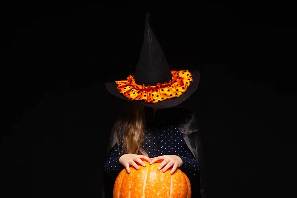 Bruja de Halloween con calabaza sobre fondo negro. Hermosa joven sorprendida mujer en sombrero de brujas y traje de calabaza celebración. Amplia fiesta de Halloween diseño de arte. Copia y pega. Concepto de bruja. Araña —  Fotos de Stock