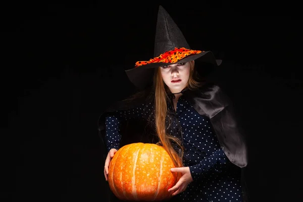 Bruja de Halloween con calabaza sobre fondo negro. Hermosa joven sorprendida mujer en sombrero de brujas y traje de calabaza celebración. Amplia fiesta de Halloween diseño de arte. Copia y pega. Concepto de bruja. Araña —  Fotos de Stock