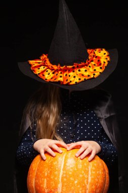Siyah arka planda Balkabağı ile Halloween Witch. Cadılar şapka ve kostüm balkabağı tutan güzel genç sürpriz kadın. Geniş Cadılar Bayramı parti sanat tasarımı. Kopyala-yapıştır. Cadı zanaat konsepti. Örümcek