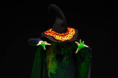 Yeşil parlayan sıvı bir tencere üzerinde Halloween Witch siyah arka plan üzerinde eller conjures. Cadılar şapka ve kostüm güzel genç sürpriz kadın . Geniş Cadılar Bayramı parti sanat tasarımı. Kopyala-yapıştır. Cadı