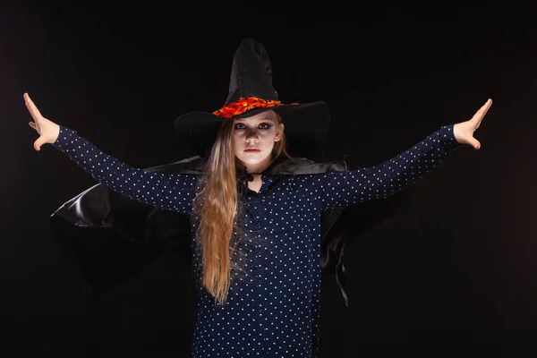 Halloween. Witch with a spider on his hat on black background. Beautiful young surprised woman in witches hat and costume holding. Wide Halloween party art design. Copy-paste. Witch craft concept. — Stock Photo, Image