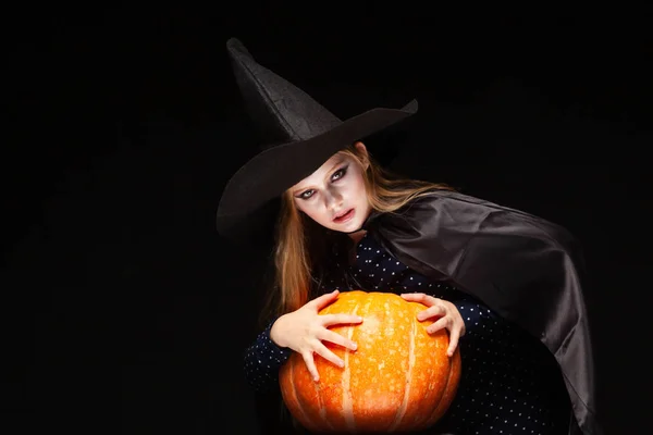 Bruja de Halloween con calabaza sobre fondo negro. Hermosa joven sorprendida mujer en sombrero de brujas y traje de calabaza celebración. Amplia fiesta de Halloween diseño de arte. Copia y pega. Concepto de bruja. Araña —  Fotos de Stock