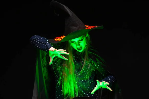 Halloween Sorcière sur un pot de liquide vert brillant évoque les mains sur fond noir. Belle jeune femme surprise en chapeau et costume de sorcières. Design d'art de fête Halloween large. Copier-coller. Sorcière — Photo