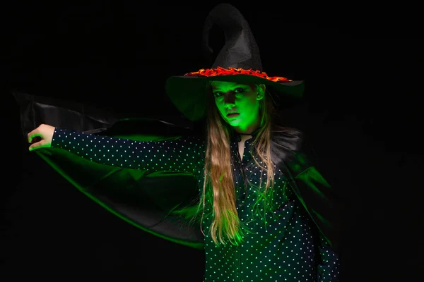 Bruja de Halloween sobre una olla de líquido verde brillante evoca las manos sobre el fondo negro. Hermosa joven sorprendida mujer con sombrero de brujas y traje. Amplia fiesta de Halloween diseño de arte. Copia y pega. Bruja. —  Fotos de Stock