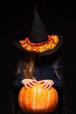 Siyah arka planda Balkabağı ile Halloween Witch. Cadılar şapka ve kostüm balkabağı tutan güzel genç sürpriz kadın. Geniş Cadılar Bayramı parti sanat tasarımı. Kopyala-yapıştır. Cadı zanaat konsepti. Örümcek