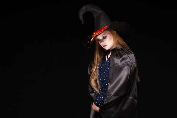 ハロウィーン。黒い背景に帽子にクモを持つ魔女。魔女の帽子と衣装を持った美しい若い驚いた女性。ワイドハロウィーンパーティーアートデザイン。コピーと貼り付け。魔術の概念 — ストック写真