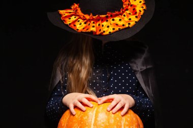 Siyah arka planda Balkabağı ile Halloween Witch. Cadılar şapka ve kostüm balkabağı tutan güzel genç sürpriz kadın. Geniş Cadılar Bayramı parti sanat tasarımı. Kopyala-yapıştır. Cadı zanaat konsepti. Örümcek