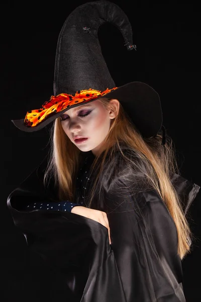 Halloween. Bruja con una araña en su sombrero sobre fondo negro. Hermosa joven sorprendida mujer en sombrero de brujas y la celebración del traje. Amplia fiesta de Halloween diseño de arte. Copia y pega. Concepto de bruja —  Fotos de Stock