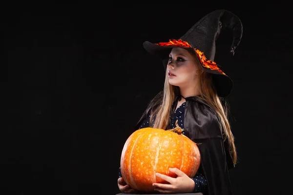 Bruja de Halloween con calabaza sobre fondo negro. Hermosa joven sorprendida mujer en sombrero de brujas y traje de calabaza celebración. Amplia fiesta de Halloween diseño de arte. Copia y pega. Concepto de bruja. Araña —  Fotos de Stock