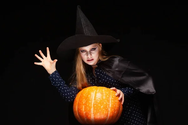 Bruja de Halloween con calabaza sobre fondo negro Lanza un hechizo con sus manos. Hermosa joven sorprendida mujer en sombrero de brujas y traje de calabaza celebración. Amplia fiesta de Halloween diseño de arte. Copiar-pegar —  Fotos de Stock