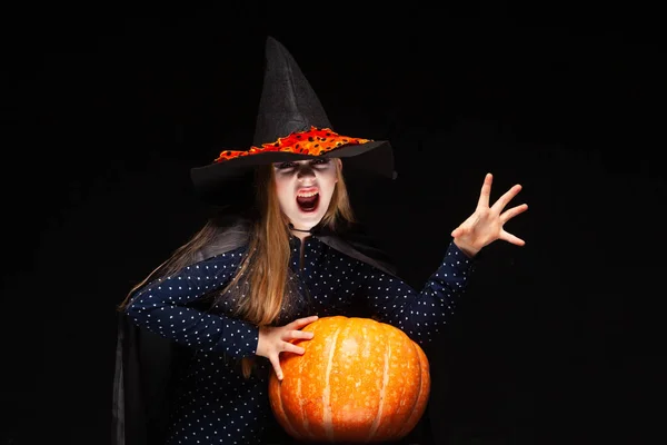Halloween boszorkány sütőtök fekete háttérrel vet egy varázslatot a kezével. Gyönyörű fiatal meglepett nő boszorkányok kalap és jelmez gazdaság sütőtök. Széles Halloween Party Art Design. Másolás-beillesztés — Stock Fotó