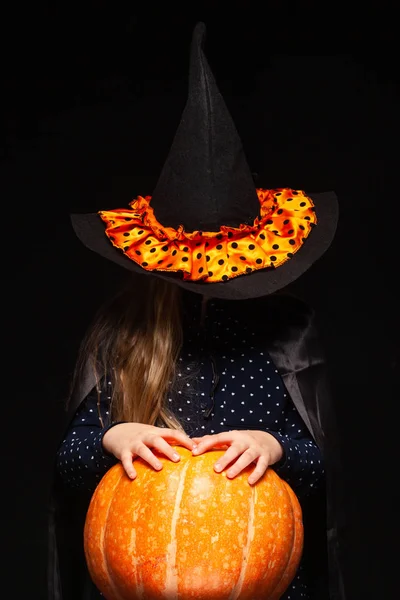 Bruja de Halloween con calabaza sobre fondo negro. Hermosa joven sorprendida mujer en sombrero de brujas y traje de calabaza celebración. Amplia fiesta de Halloween diseño de arte. Copia y pega. Concepto de bruja. Araña —  Fotos de Stock