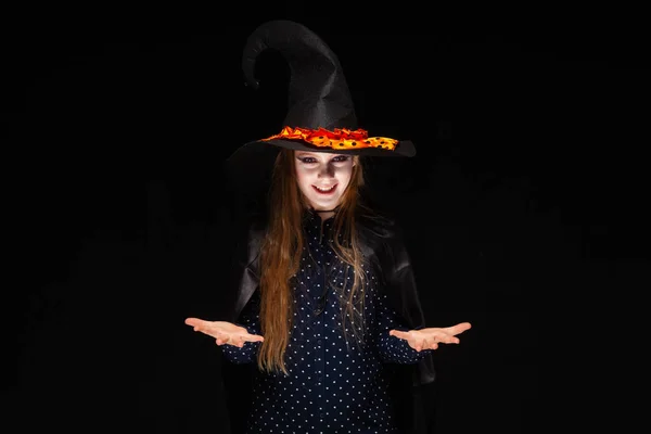 Halloween čarodějka na černém pozadí. Krásná mladá překvapená žena v čarodějové čepici a kostýmech. Široký Halloween umělecký design. Kopírovat-vložit. Koncepce vah, nabídky k výběru dárků, umístění položek — Stock fotografie