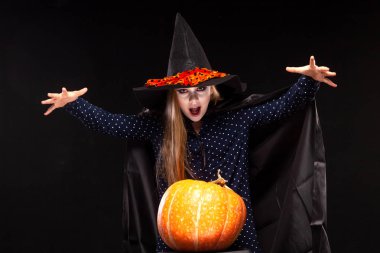 Siyah arka plan üzerinde Kabak ile Halloween Witch elleriyle bir büyü casts. Cadılar şapka ve kostüm balkabağı tutan güzel genç sürpriz kadın. Geniş Cadılar Bayramı parti sanat tasarımı. Kopyala-yapıştır