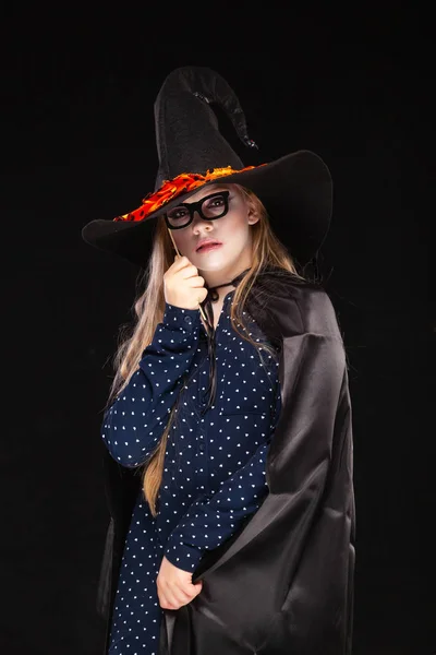 Halloween Witch with Pumpkin on black backgroundin a fancy mask. Beautiful young surprised woman in witches hat and costume holding. Wide Halloween party art design. Copy-paste. Witch craft concept