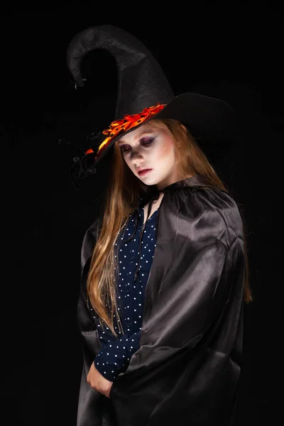 Απόκριες. Μάγισσα με μια αράχνη στο καπέλο του σε μαύρο φόντο. Όμορφη νεαρή έκπληκτη γυναίκα σε μάγισσες καπέλο και κοστούμι κρατώντας. Πλατύ αποκριάτικο σχέδιο. Αντιγραφή-επικόλληση. Ιδέα για τα μαγικά σκάφη — Φωτογραφία Αρχείου