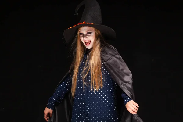 Halloween. Witch with a spider on his hat on black background. Beautiful young surprised woman in witches hat and costume holding. Wide Halloween party art design. Copy-paste. Witch craft concept