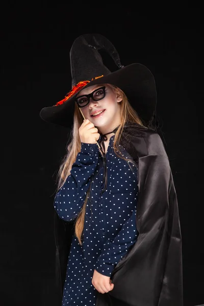 Halloween Witch with Pumpkin on black backgroundin a fancy mask. Beautiful young surprised woman in witches hat and costume holding. Wide Halloween party art design. Copy-paste. Witch craft concept