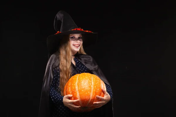 Bruja de Halloween con calabaza sobre fondo negro. Hermosa joven sorprendida mujer en sombrero de brujas y traje de calabaza celebración. Amplia fiesta de Halloween diseño de arte. Copia y pega. Concepto de bruja. Araña —  Fotos de Stock