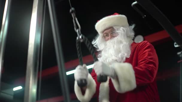 Санта Клаус тренируется в спортзале на Рождество. Санта-Клаус работает над упражнениями в трицепсе . — стоковое видео