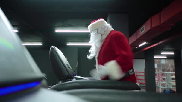 Santa Claus training at the gym on Christmas Day. Santa Claus running in machine treadmill at fitness gym club — 图库视频影像