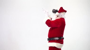 Noel zamanı. Beyaz arka planda, sanal gerçeklik gözlükleriyle Noel Baba bilgilerle çalışır ve ellerini sallar. Vr