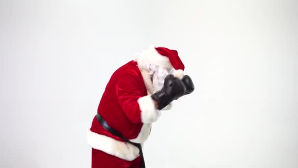 No Natal. Papai Noel em um fundo branco usa luvas de boxe preto e cumpre socos. Kickboxing, lutador . — Vídeo de Stock