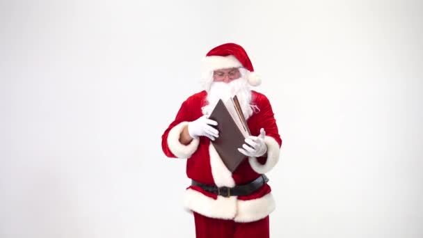 圣诞节。 白色背景的圣诞老人穿着皮革封皮读一本大书。 一页一页一页地翻. — 图库视频影像