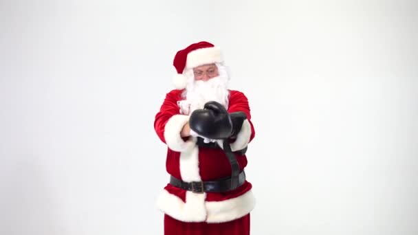 Kerstmis. Kerstman op een witte achtergrond draagt zwarte bokshandschoenen en vervult stoten. Kickboksen, vechter. — Stockvideo