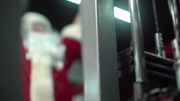 Santa Claus trénuje v tělocvičně na Štědrý den. cvičební stroj. — Stock video