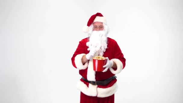 Kerstmis. Kerstman op een witte achtergrond met een rode emmer met popcorn. Er is popcorn, films kijken, emoties, angst, plezier. — Stockvideo