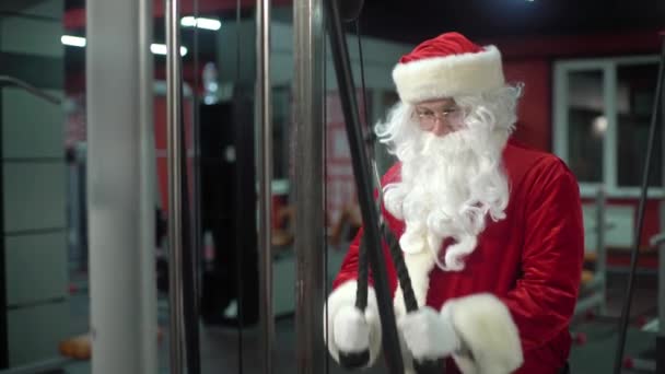 Santa Claus entrenando en el gimnasio el día de Navidad. Santa Claus trabajando haciendo ejercicios en tríceps . — Vídeos de Stock