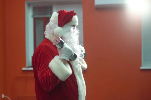 Trening Świętego Mikołaja na siłowni w Boże Narodzenie. Święty Mikołaj ćwiczy z hantlami. — Zdjęcie stockowe