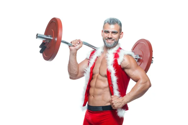 Sexy Santa Claus. Culturista joven guapo Santa Cláusula sonrisa sostiene una barra con tortitas rojas en el hombro y muestra los cubos abdominales en la víspera de Año Nuevo y Navidad vacaciones de invierno fondo blanco — Foto de Stock