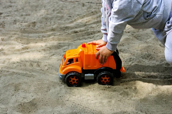Children's sand games. The child carries a large plastic machine on the sand.