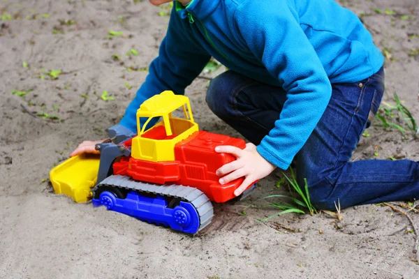 Children\'s sand games. A child playing on the sand with a toy car.