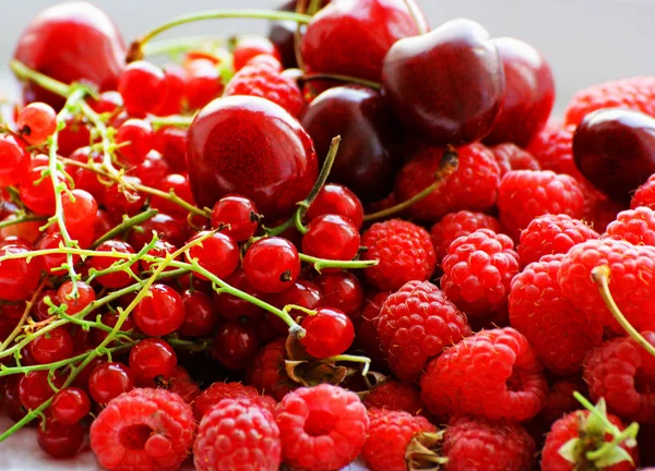 The berries in the bunch. Berries of ripe red raspberry, currants and cherries are poured into one big pile.