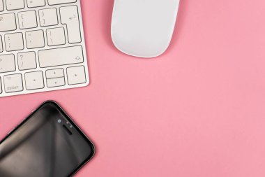 Bilgisayar klavyesi ve diğer ofis malzemeleri ile pembe ofis masası arka plan. Kopyalama alanı ile üst görünüm, düz döşeme.