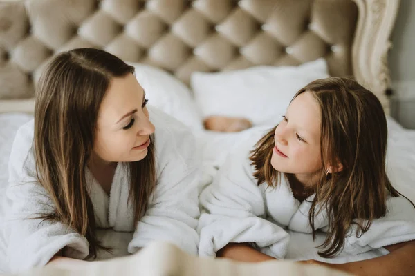 Mom and daughter are fighting pillows on the bed, pillow fight