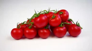 Kız eli beyaz arka planda domates ve kiraz domatesleri alır.