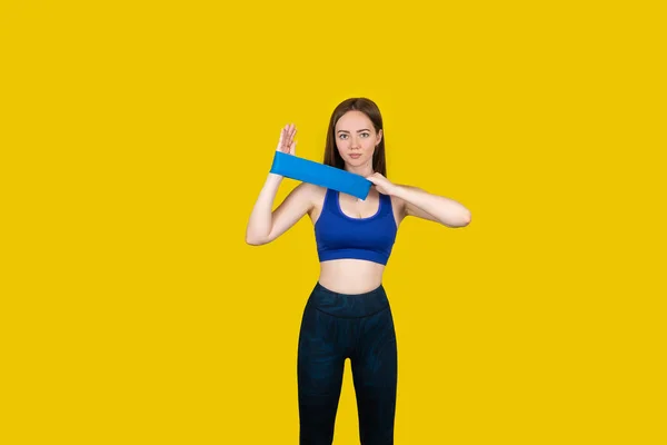 Girl in sports uniform with a cup of water and a phone in hands against a yellow background — Stock Photo, Image