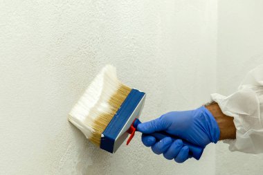 Ressam olan beyaz renk tonunu duvar boyar. Duvar ciddi nem sorunları olan. Ayrıntı fırça. beyaz boya ressamın iş için hazırlanır.