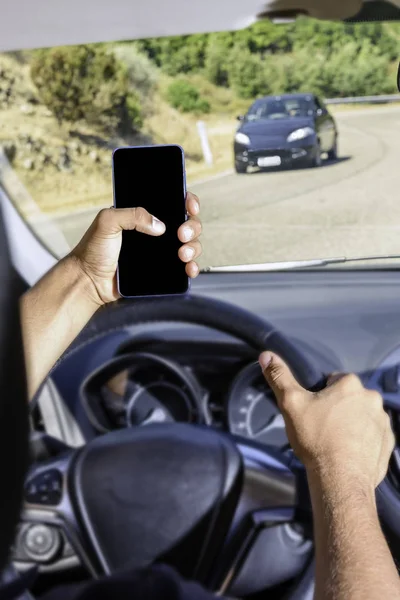 Jonge bestuurder, met behulp van smartphone, op de weg in de auto. — Stockfoto