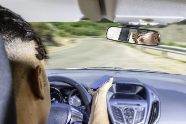 Młody kierowca, za pomocą smartfona, na drodze w samochodzie. — Zdjęcie stockowe