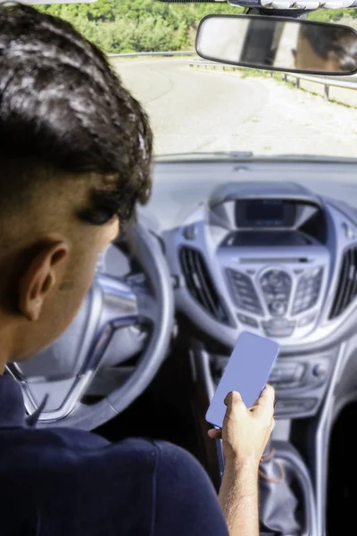 Joven conductor, usando smartphone, en la carretera en el coche . —  Fotos de Stock