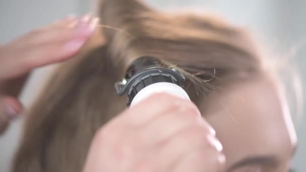 Crear peinados en una joven rubia. Gira tu cabello plano . — Vídeos de Stock